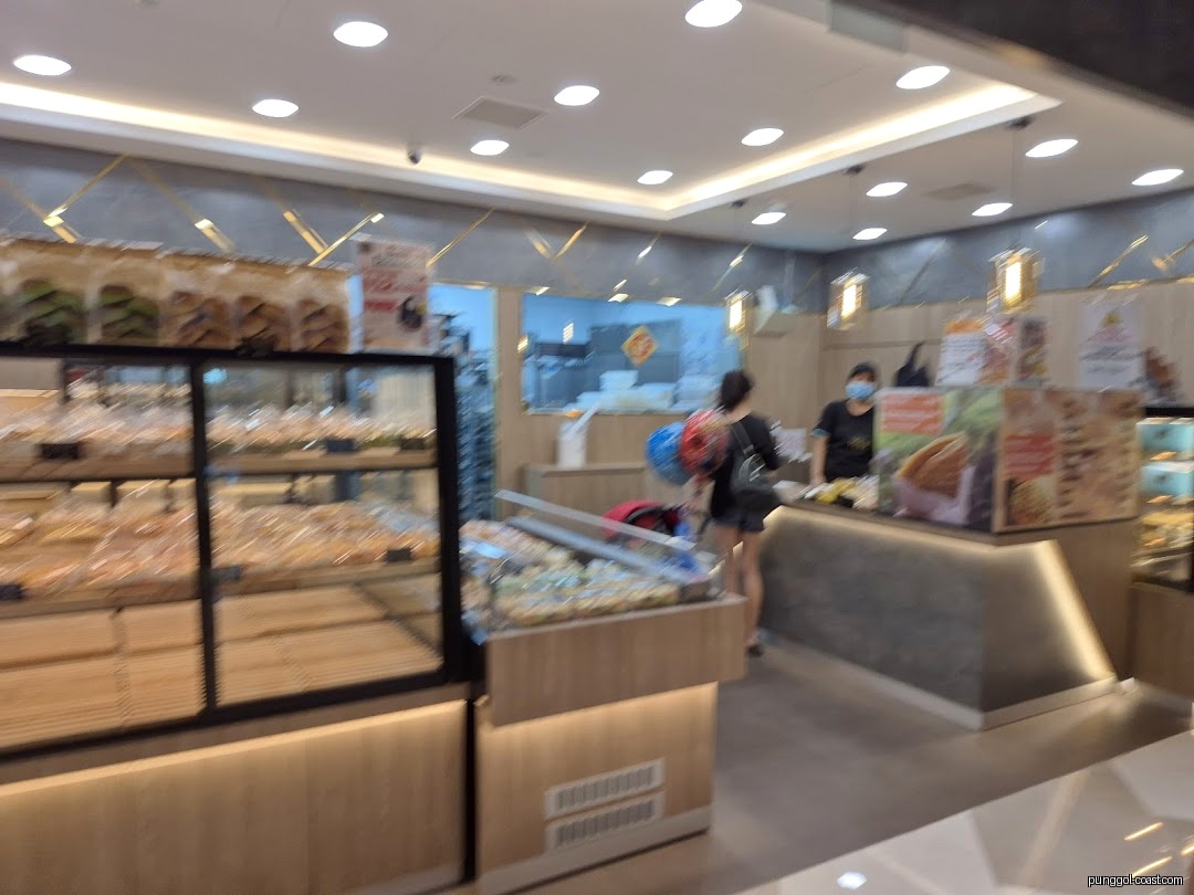 Interior view of a bakery with display cases, customers, and staff.