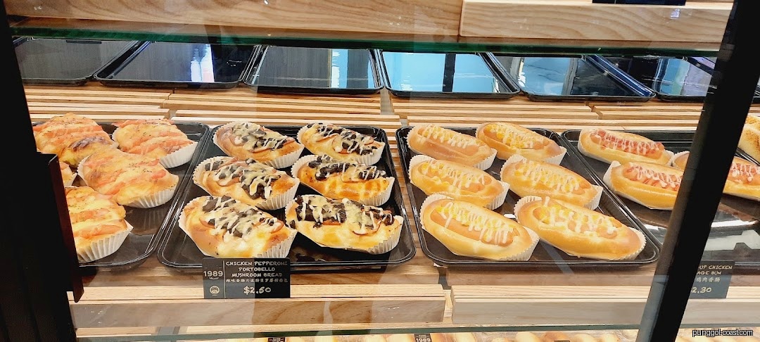 Close-up of various baked goods, including buns and breads, in a display case.