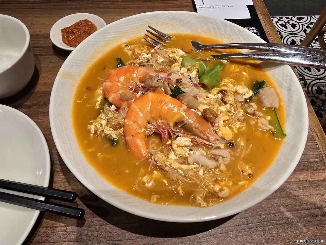 Close-up of a delicious bowl of prawn noodles with egg and chopsticks.