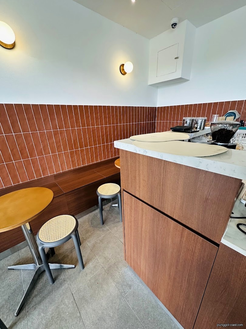 Interior view of a shop with a counter, seating, and tiled wall.