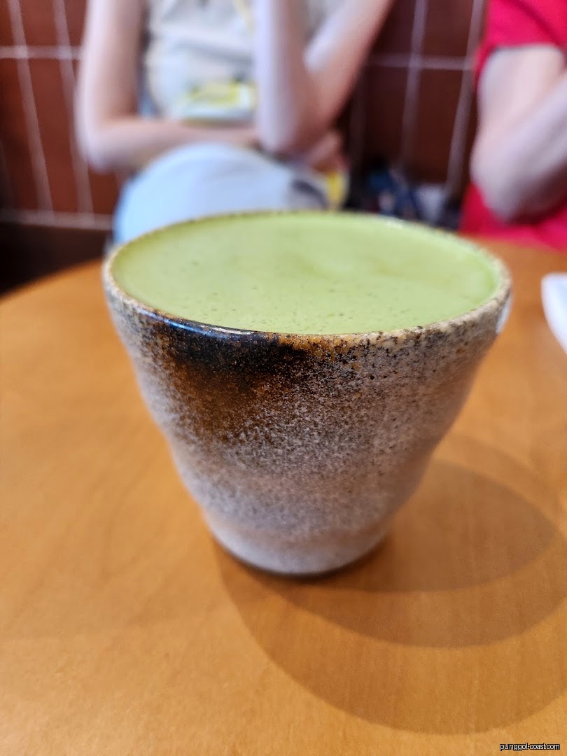 Close-up of a green beverage in a cup on a wooden table.