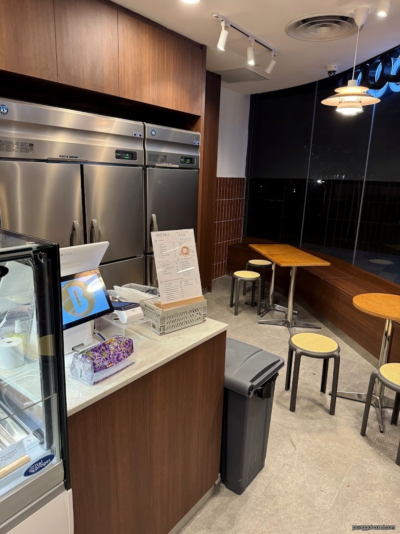 Shop interior showing counter, refrigerators, menu stand, and customer seating.