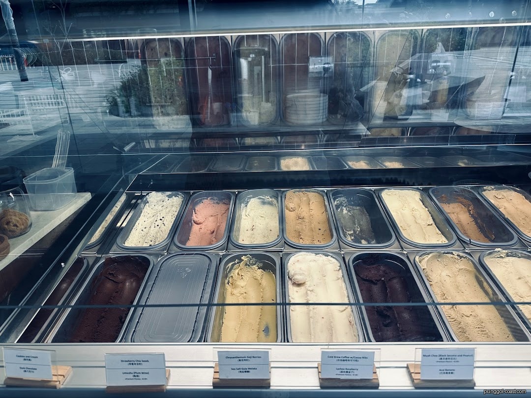 Various ice cream flavors are displayed in a glass freezer case.