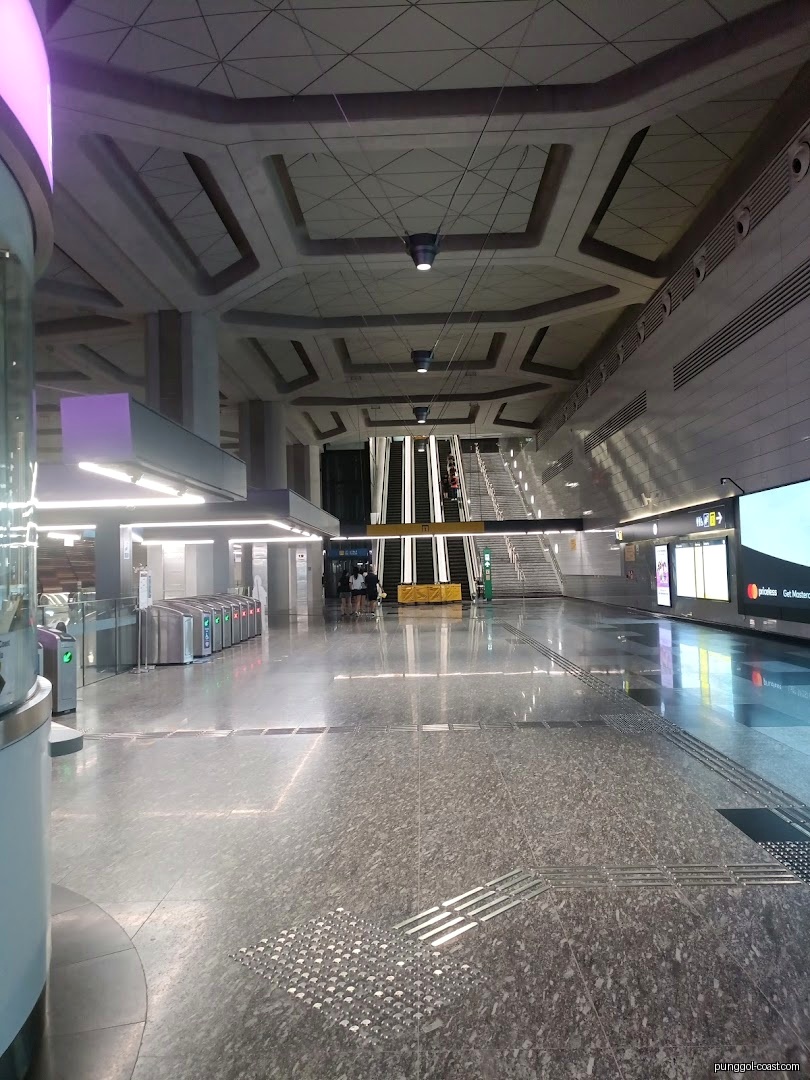 Spacious, modern subway station interior with escalators and turnstiles.