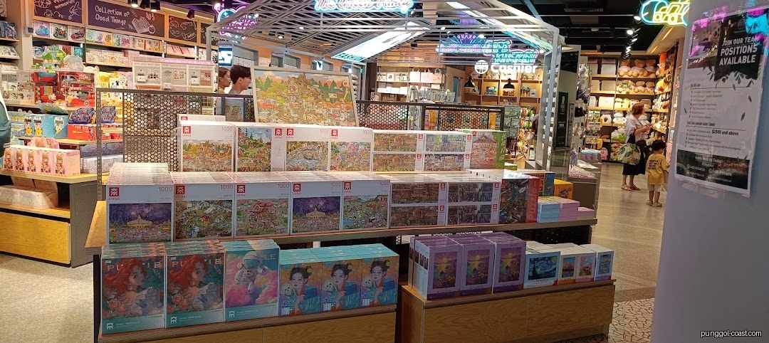 Shop interior with displays of puzzles and various products, customers browsing.