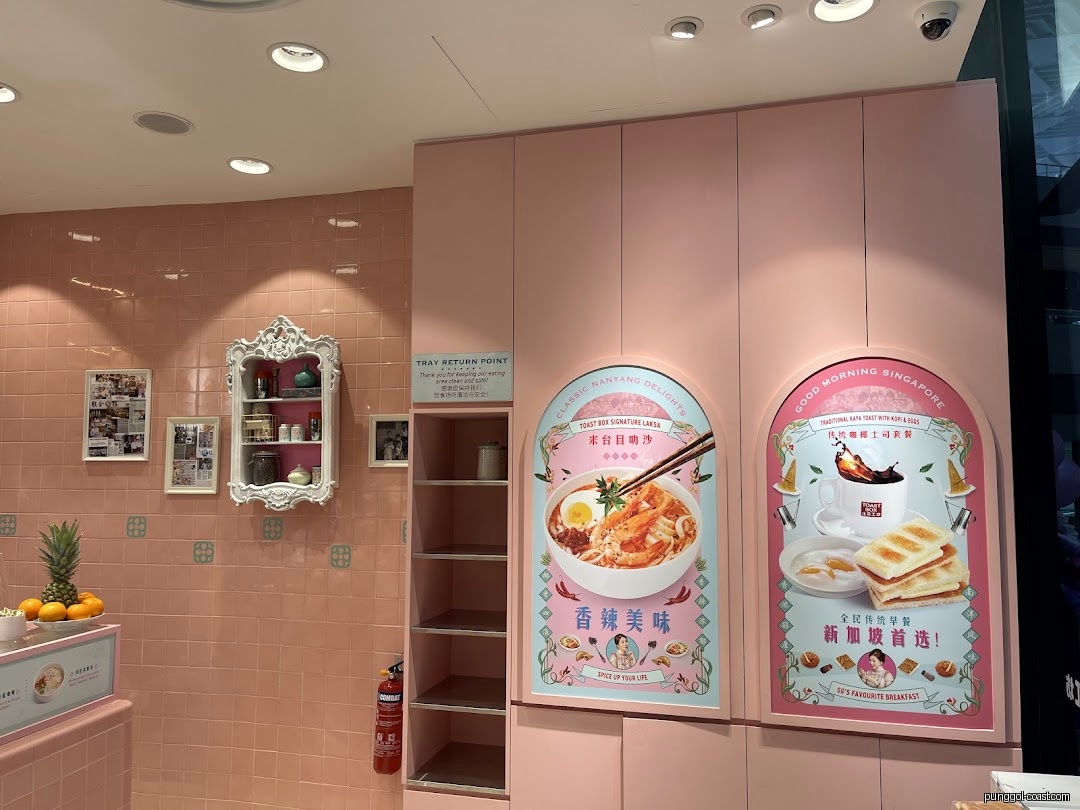 Pink-themed shop interior with food display boards and a counter.