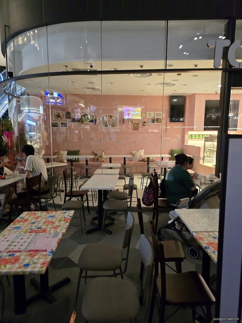 Interior view of a cafe with pink walls, tables, chairs, and customers.