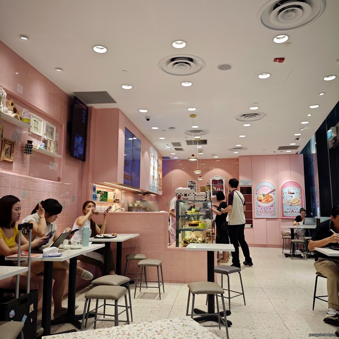 Pink-themed cafe interior with customers, tables, and a service counter.