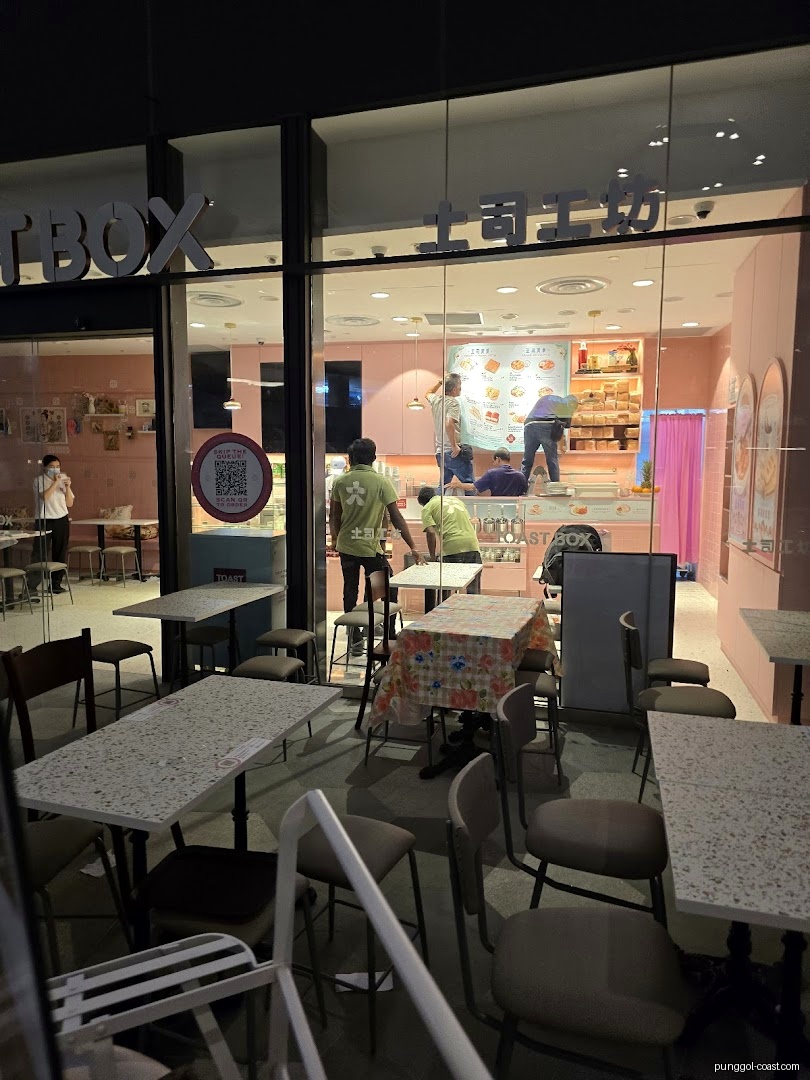 Toast Box shop front at night with interior visible through glass windows.