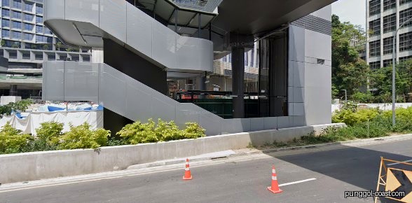 Modern building exterior with stairs, road, and greenery under construction.