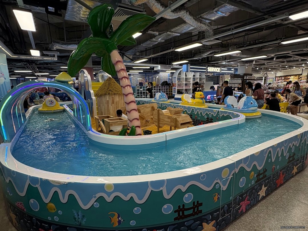 Indoor water play area with small boats, a palm tree, and sandpit elements.