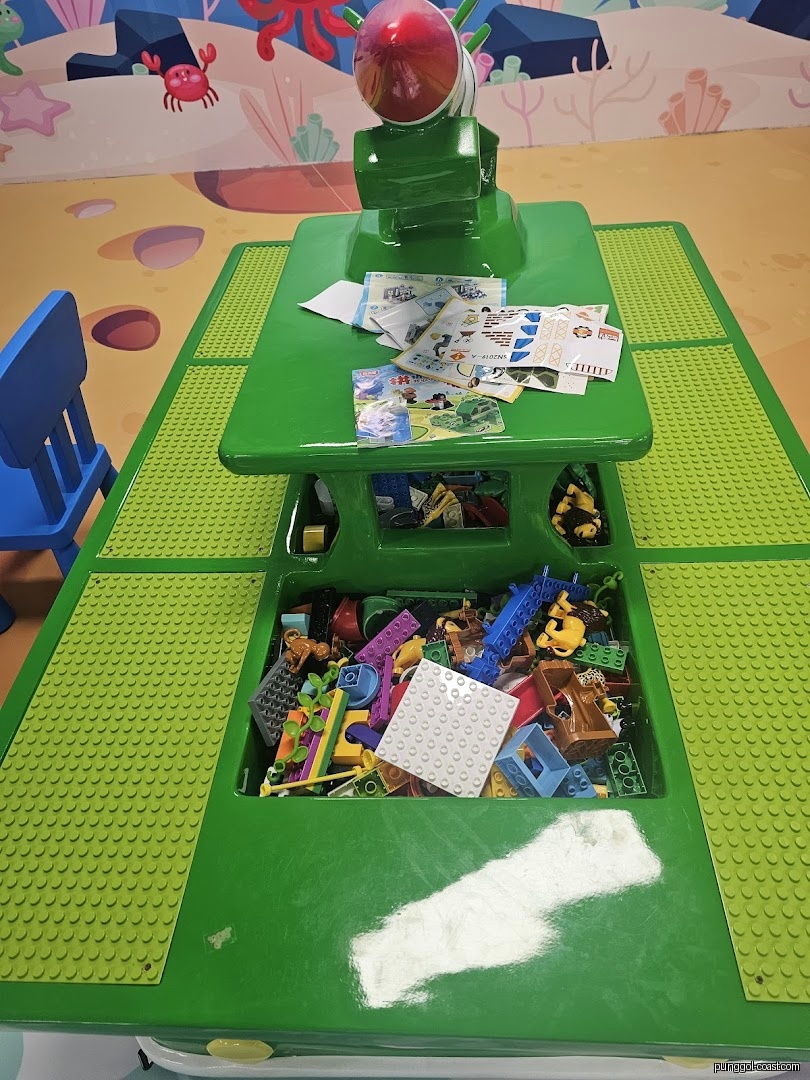 Play area with green building block table and ocean-themed mural.