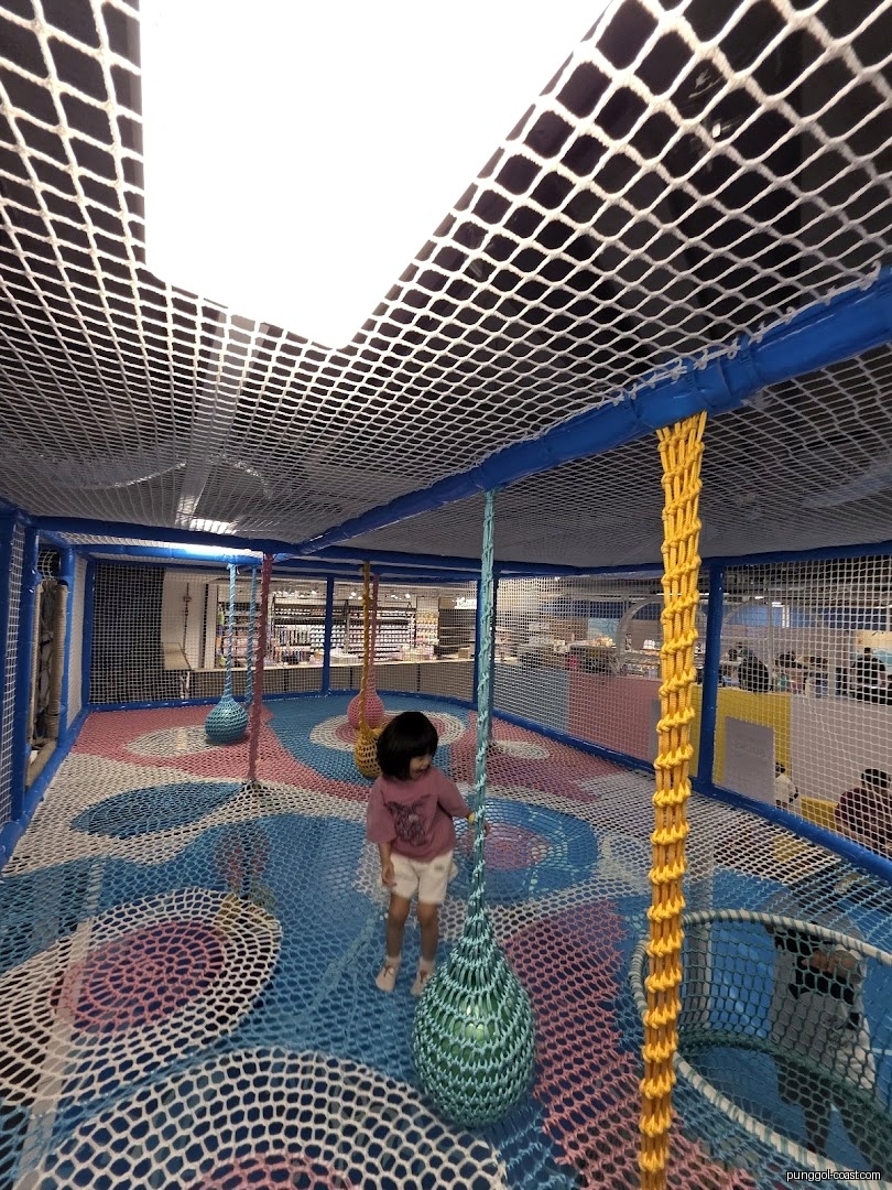 A child plays in a colorful netted indoor playground.
