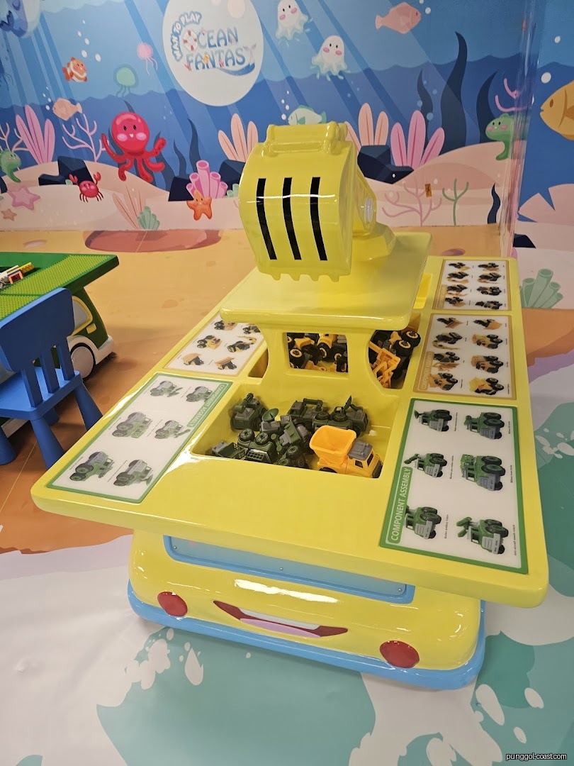 Yellow play table with toy construction vehicles inside an ocean-themed room.