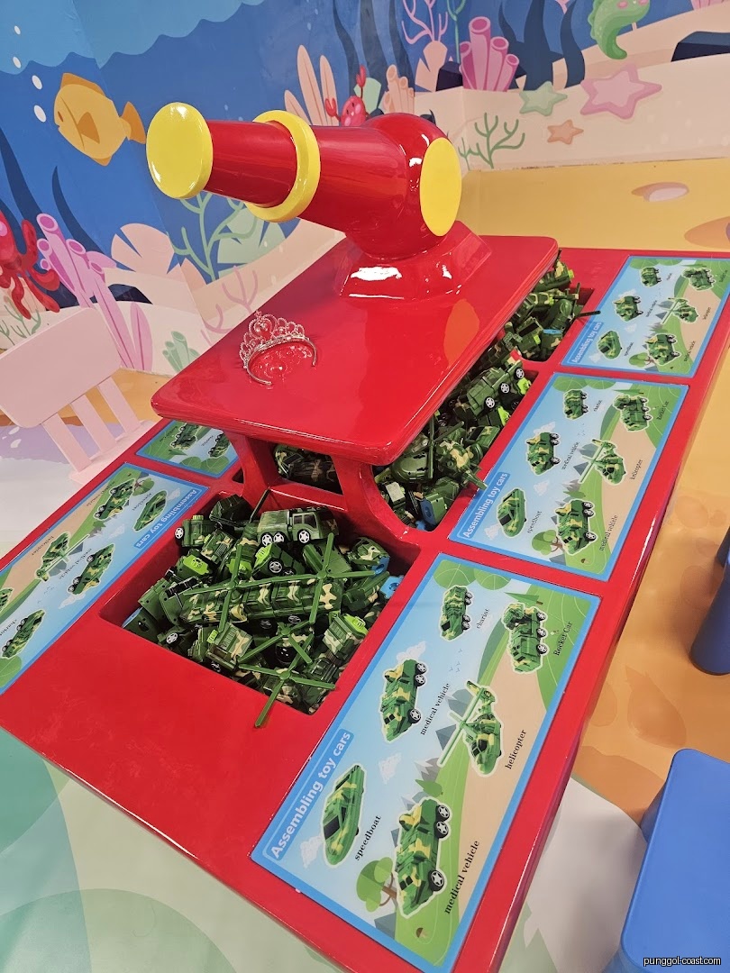 Interior shot of a play area with a red table and toy cars.