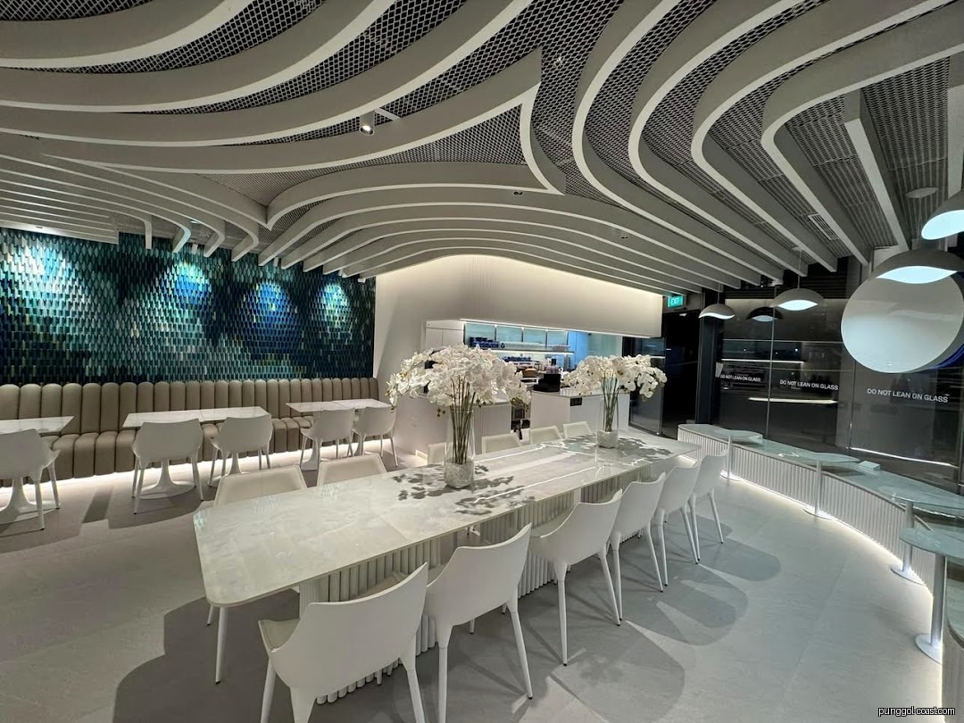 Spacious, modern cafe interior featuring white furniture and a textured blue wall.