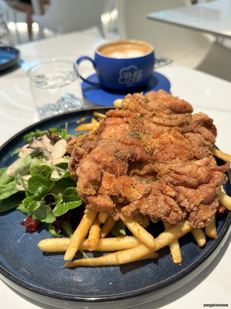 Fried chicken, fries, salad, and coffee on a table.