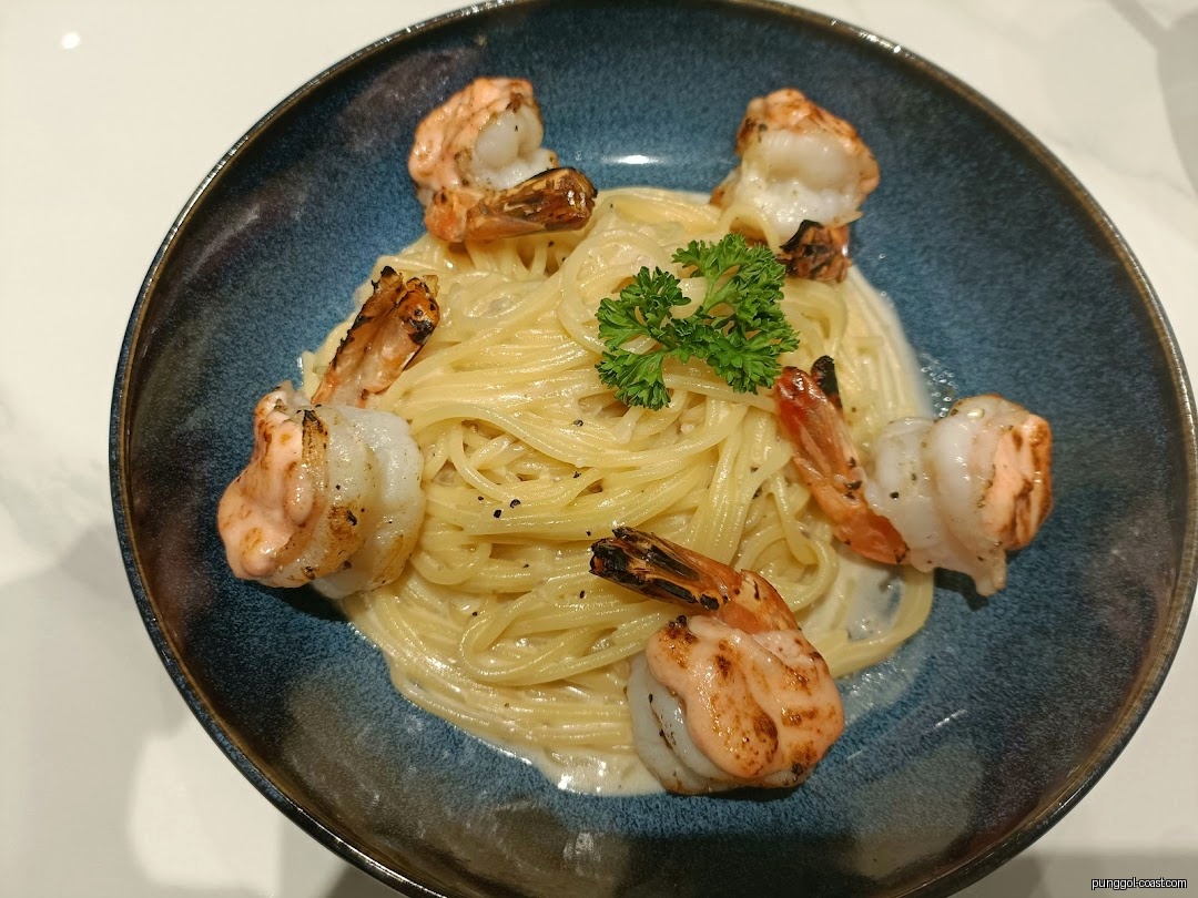 Creamy pasta with grilled shrimp and parsley in a blue bowl.