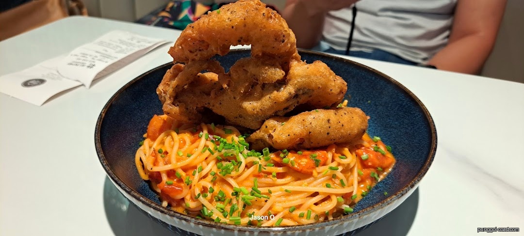 Close-up of spaghetti with fried seafood in a blue bowl on a table.