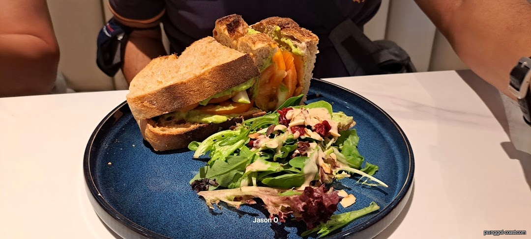 A sandwich and side salad on a blue plate at a cafe.