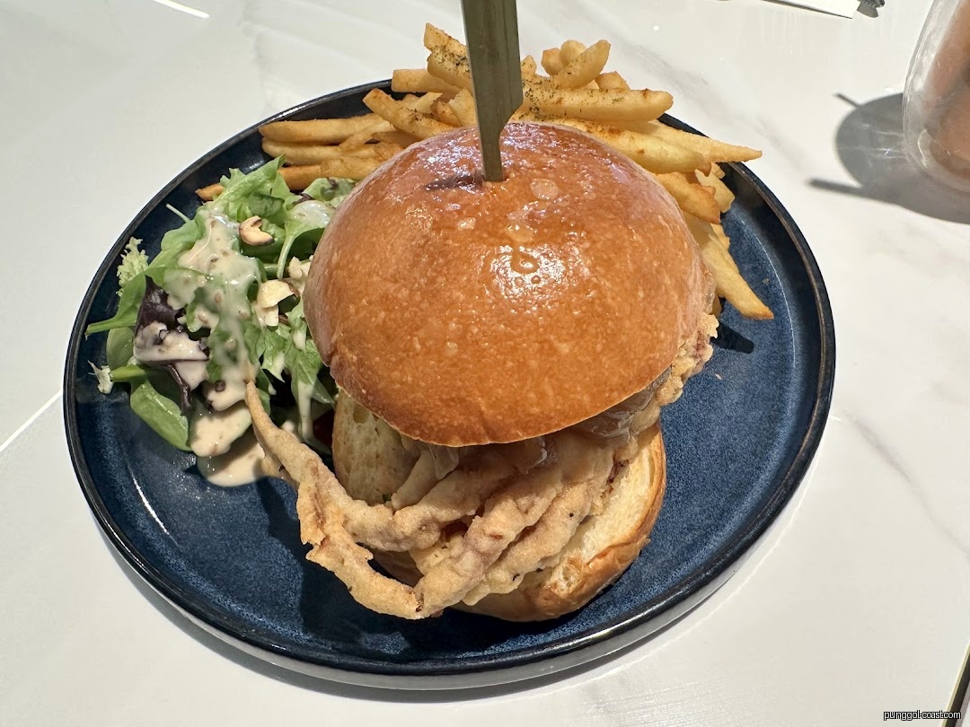 A plate with a burger, fries, and salad on a white table.