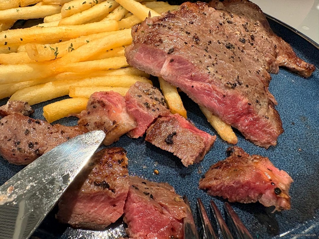 Close-up of a steak and french fries on a blue plate with cutlery.