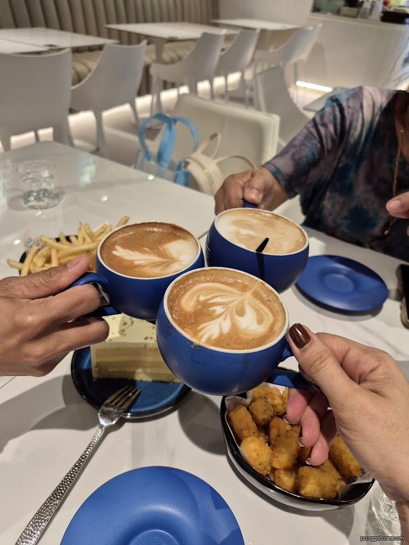 People holding coffee cups and food on a table in a modern cafe.