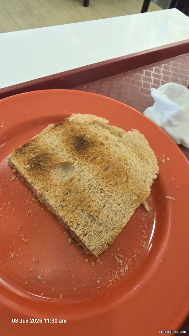 A piece of toasted bread on an orange plate with crumbs.