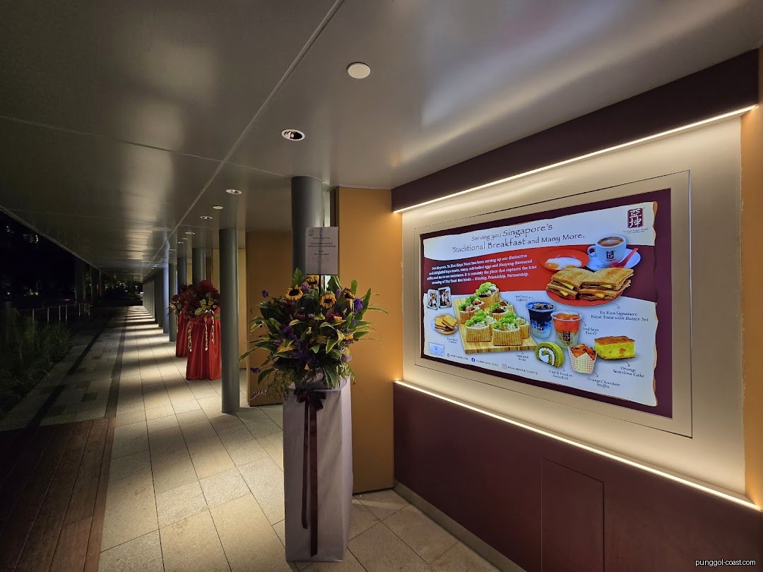 Illuminated menu board and flowers in a shop's entrance walkway.