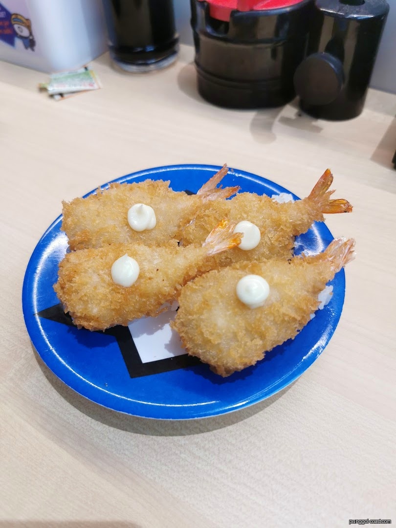 Four fried shrimp with mayonnaise on a blue plate.