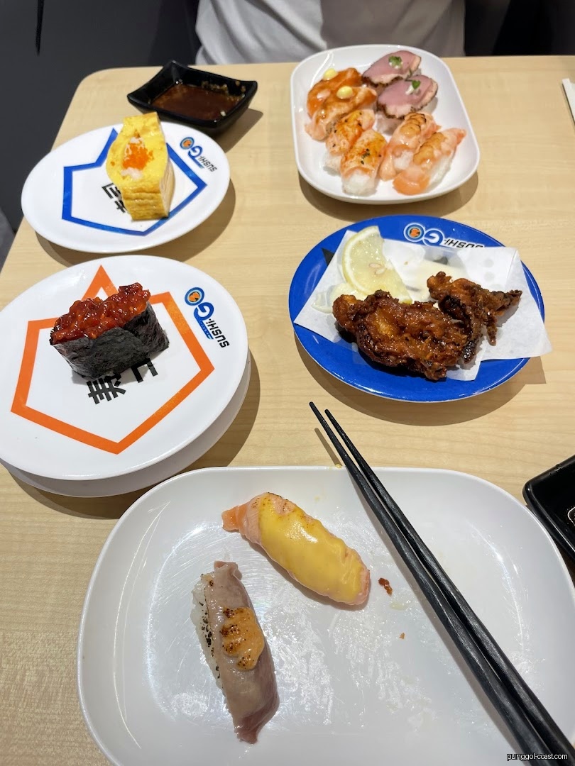 Various sushi and fried chicken dishes on a table at Sushi-GO.