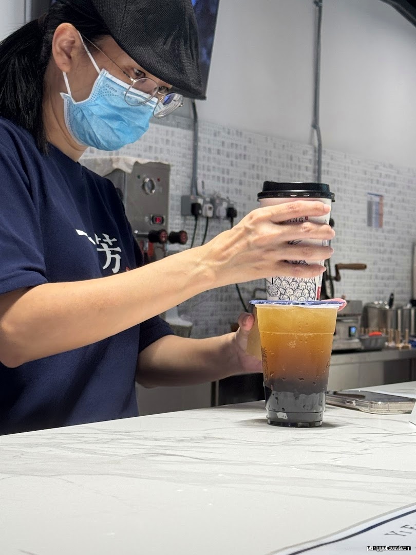 Staff member preparing a layered drink behind a counter.