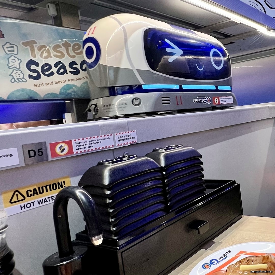 Sushi restaurant interior with robot delivery on conveyor belt and stacked plates.