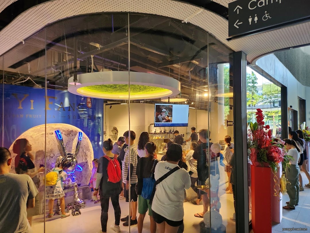 Interior view of a busy fruit tea shop with customers and a large rabbit sculpture.