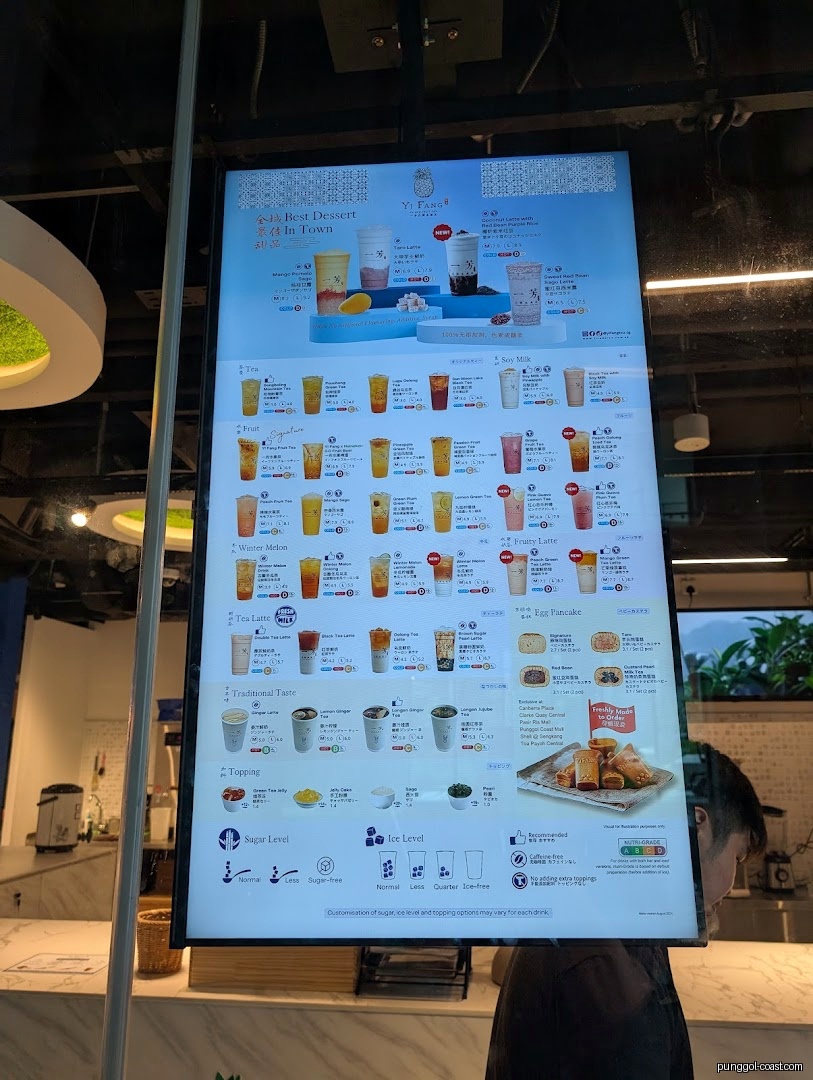 Digital menu board displaying various fruit teas, lattes, and toppings.