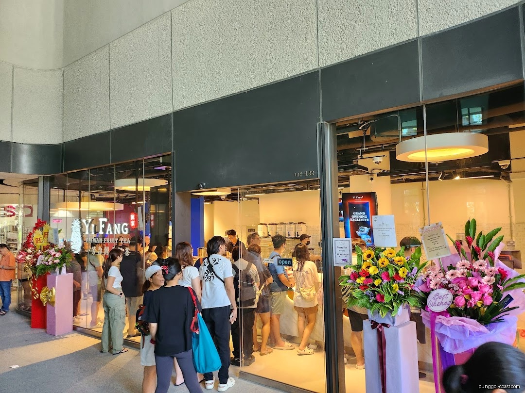 Shop front of Yi Fang Taiwan Fruit Tea with queuing customers and flowers.