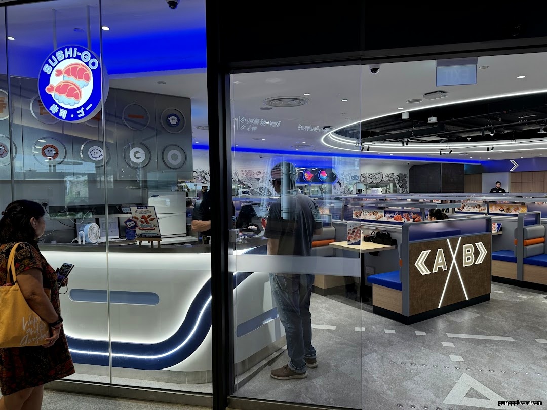 Sushi-GO shop entrance showing counter, interior seating, and customers.